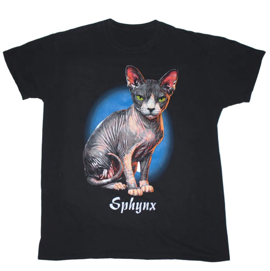 A black short-sleeve t-shirt featuring a graphic of a hairless cat (Sphynx) sitting in front of a blue circular background, with the word 'Sphynx' printed below in white gothic-style lettering.